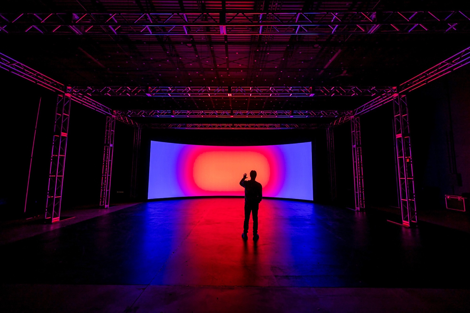 The empty LED volume glowing red and blue under the truss, with one person standing in front of it